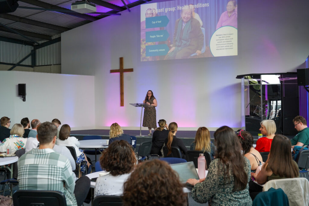 A woman on stage addressing the room.