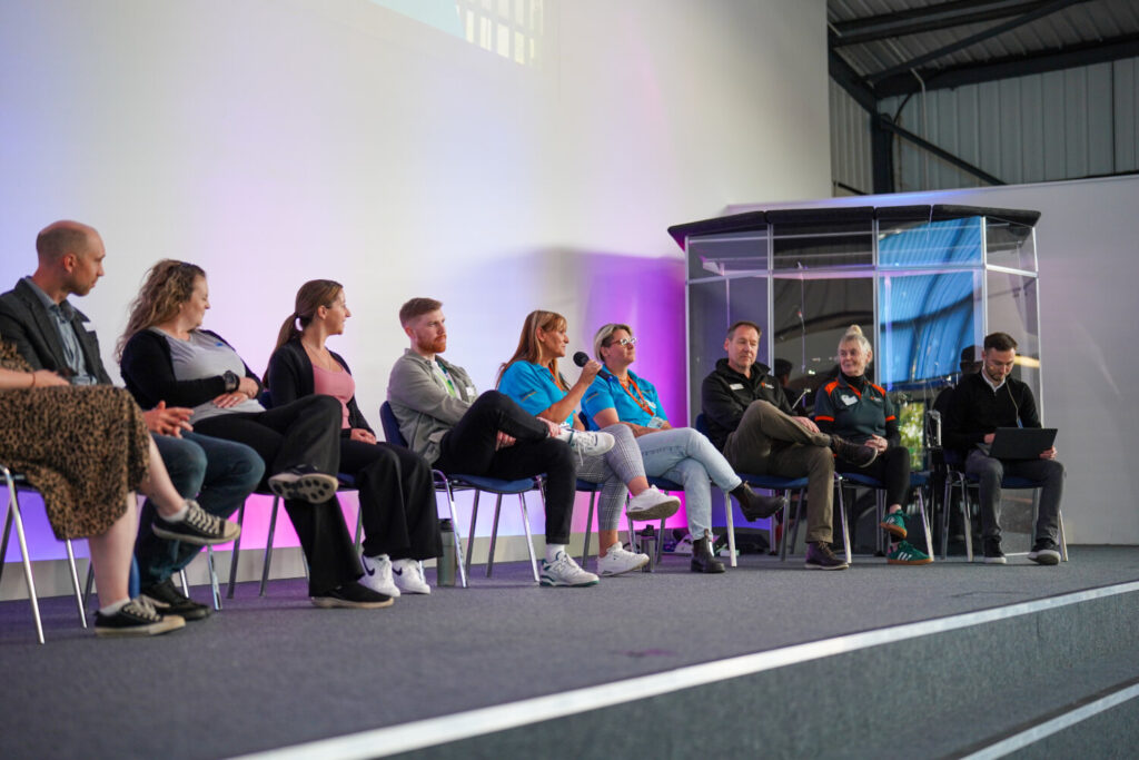 A group of people sat on the stage. One is talking into a microphone.