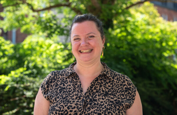 A woman in leopard print dress, smiling. Outside.