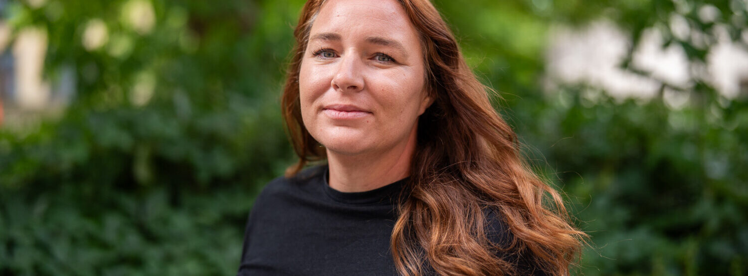A woman with light brown hair wearing a black top.