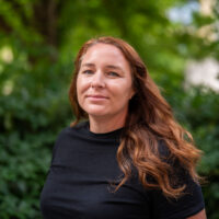 A woman with light brown hair wearing a black top.