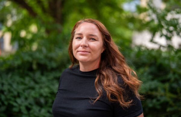A woman with light brown hair wearing a black top.