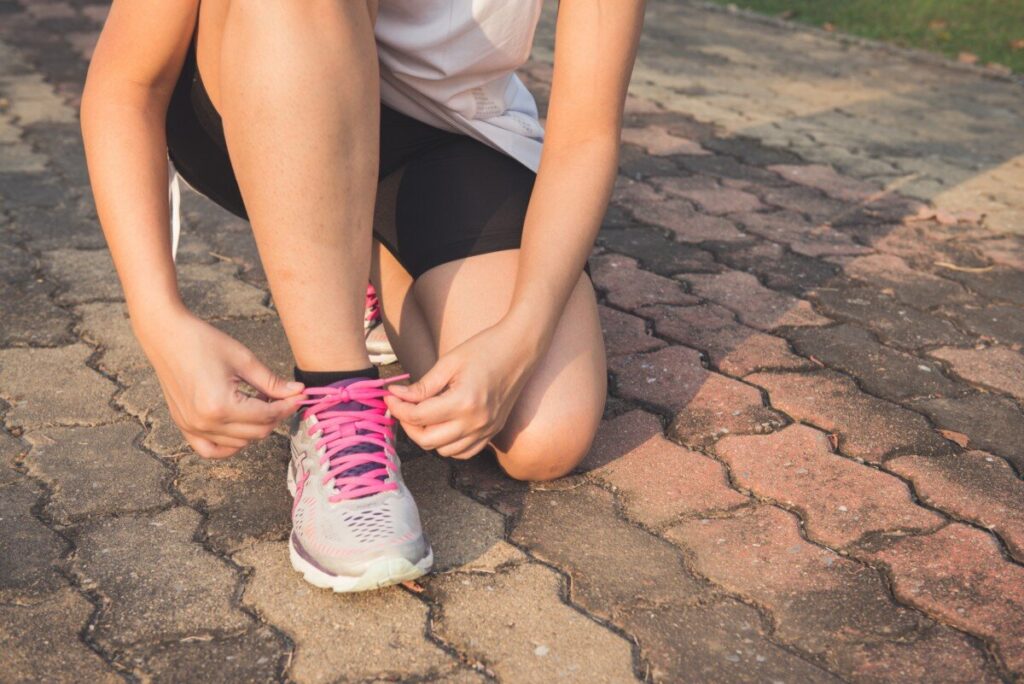 Women running tying shoe (Returning to physical activity)