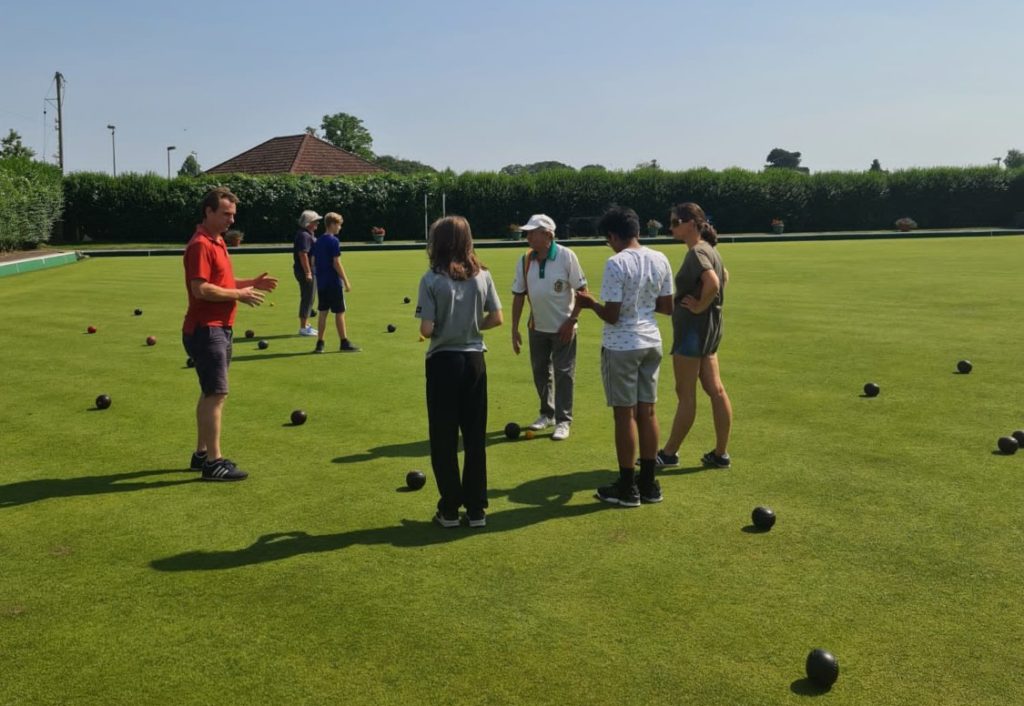 Bowls volunteer instructing the boys how to play