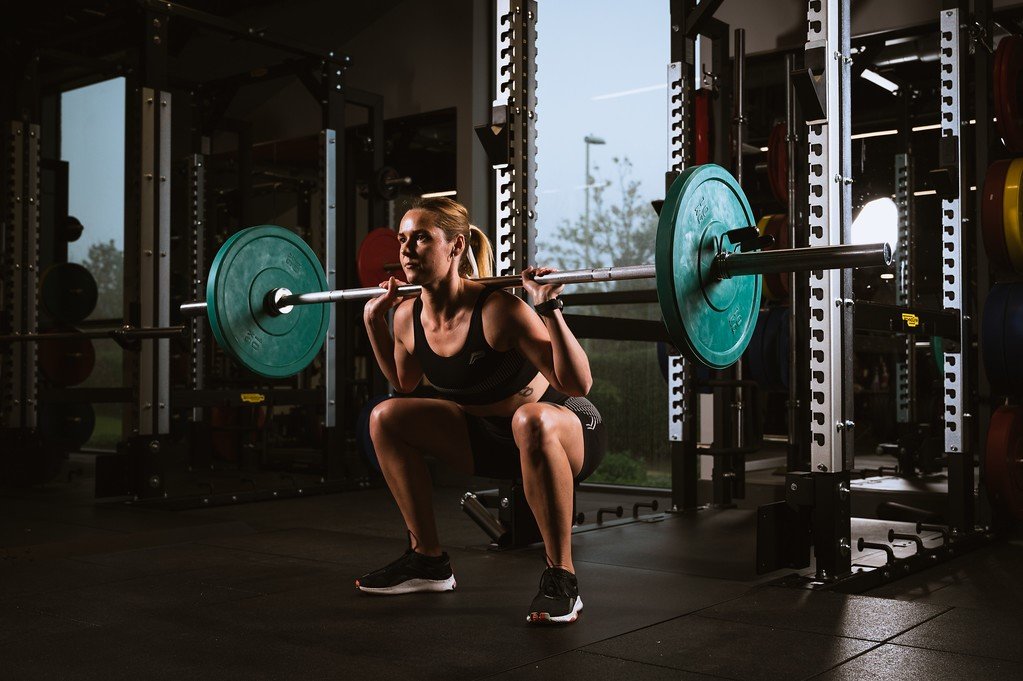 Yasmine showing she is a strong woman squatting with a barbell 