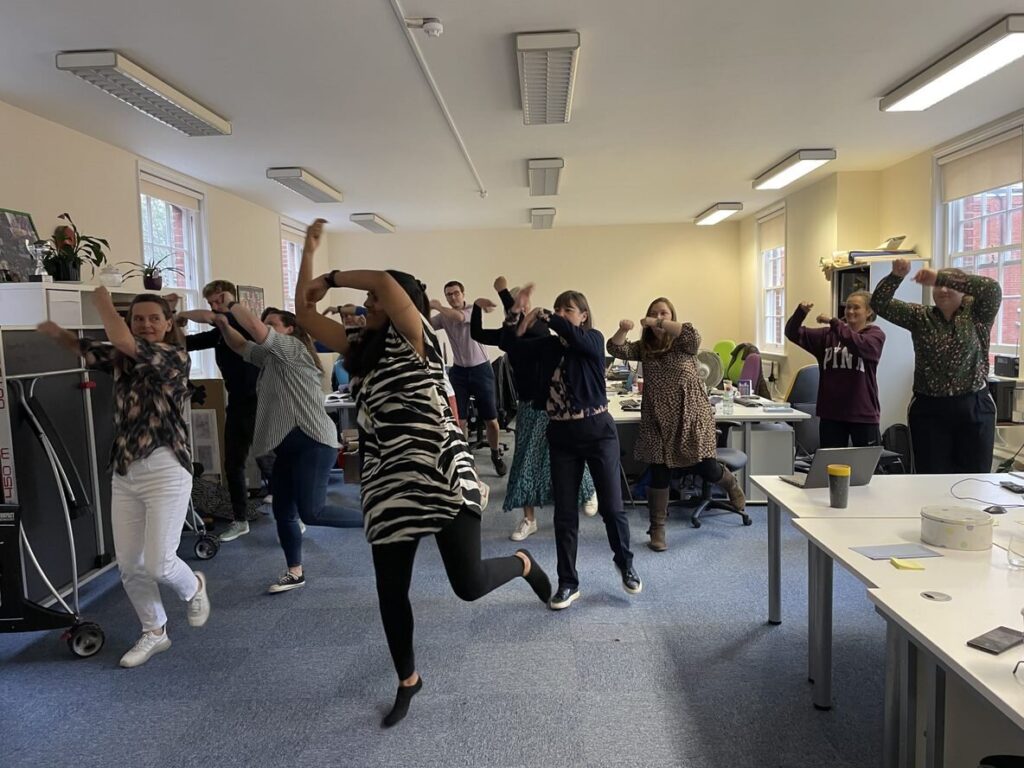 A group of people in an office dancing.