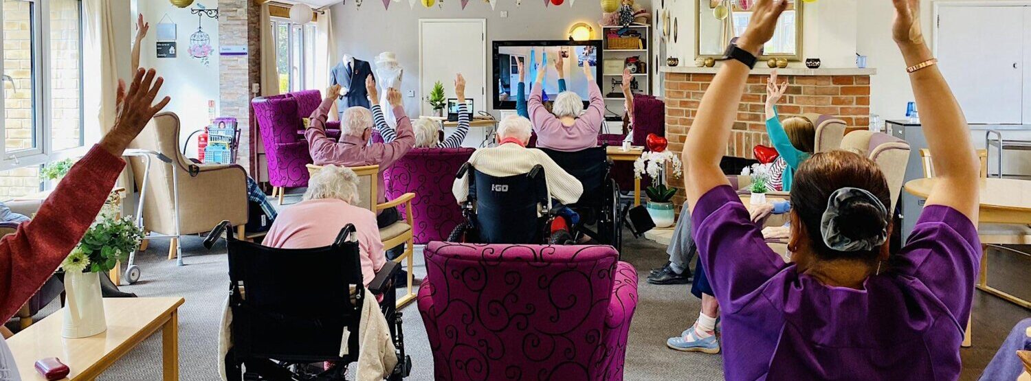 A group of older people taking part in chair based exercise in a care envrionment.