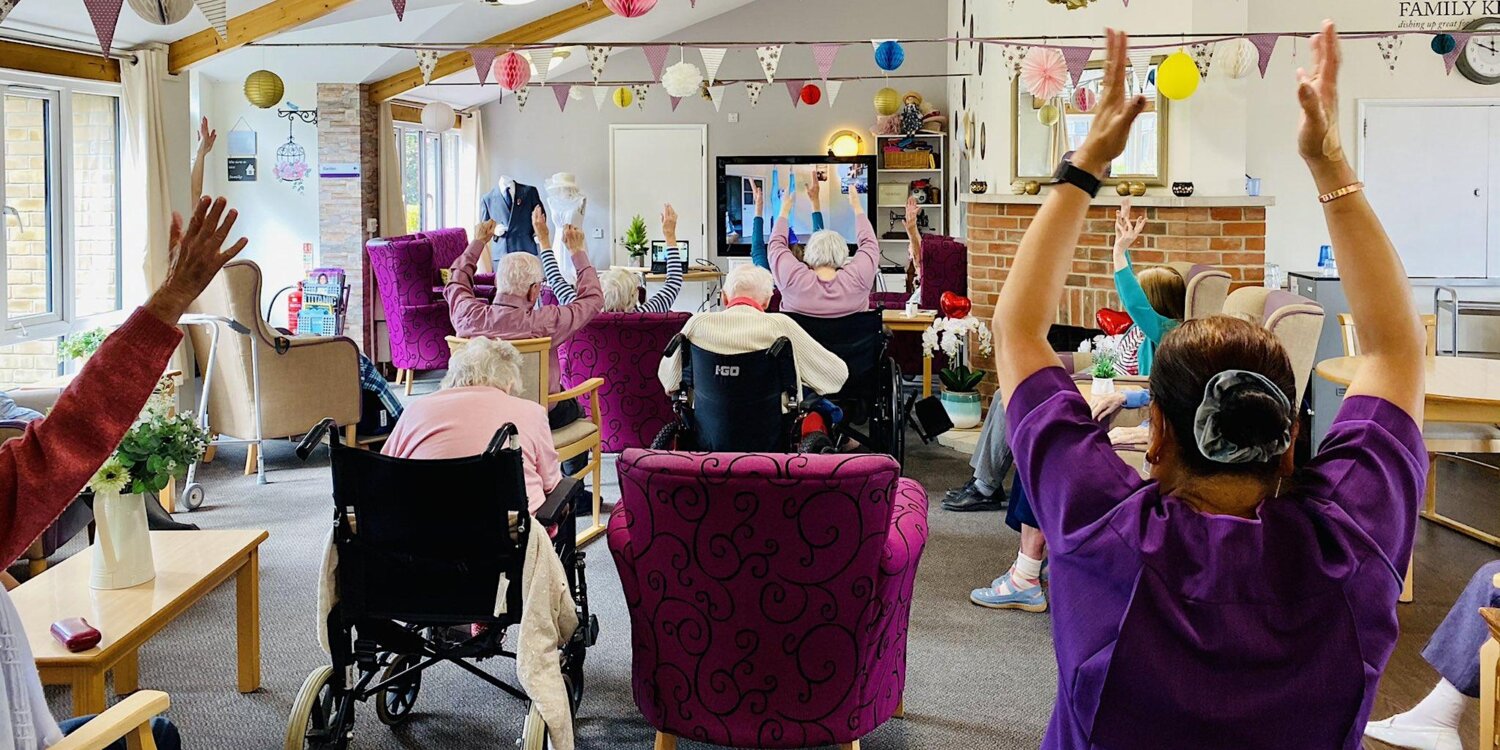 A group of older people taking part in chair based exercise in a care envrionment.