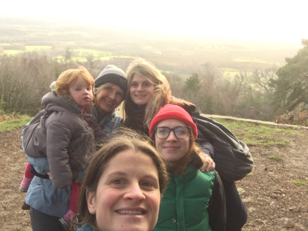 A group of women and a child at the top of a hill smiling.