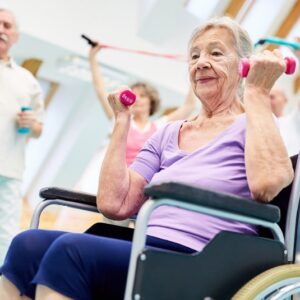 A group pf older adults, some are seated and some standing. They are using small weights and bands to complete upper body exercises.