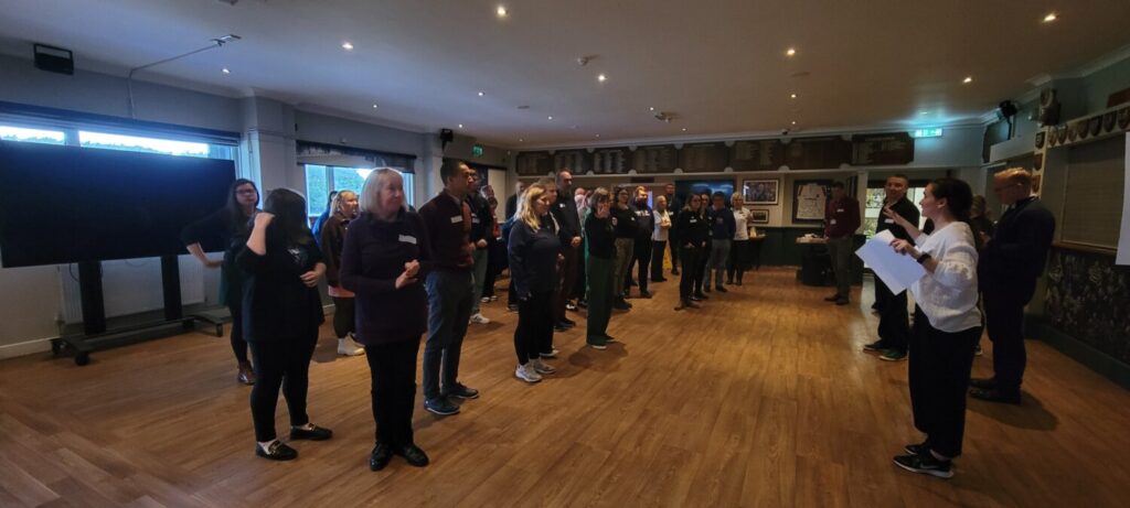 A group of people spread out in a line across a large room.