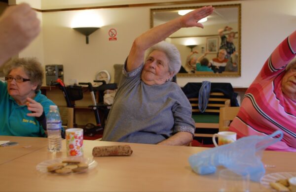 A group in a residential care setting stretching in chair exercises