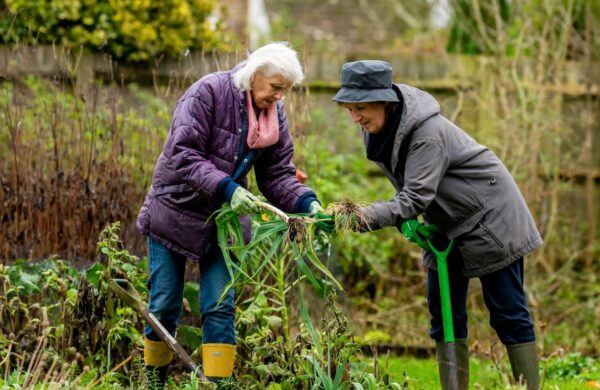 Two women in coats gardening.