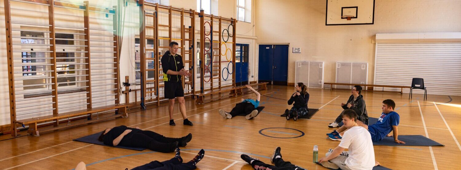 A group of young people lying on yoga mats in a gymnasium.