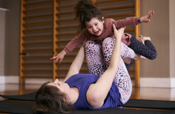 A woman lying on her back with her child on her knees.