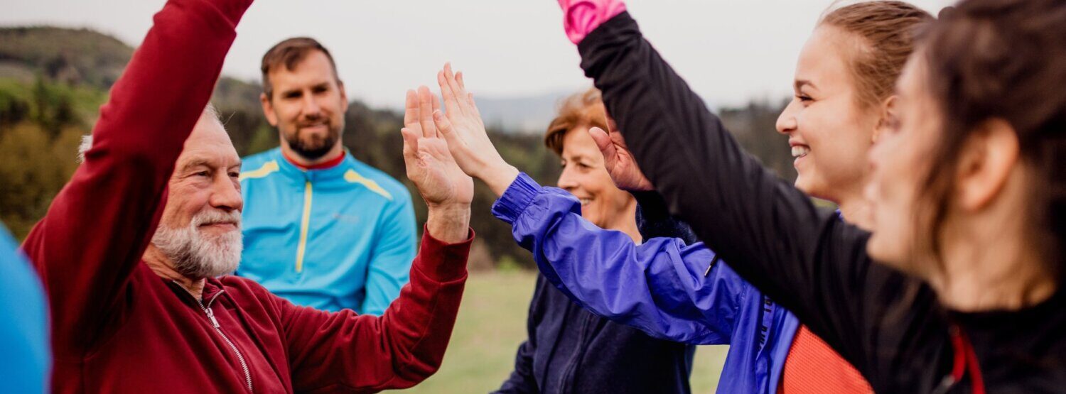 A group of men and women of all ages, outdoors, celebrating with each other.