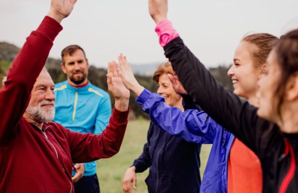 A group of men and women of all ages, outdoors, celebrating with each other.