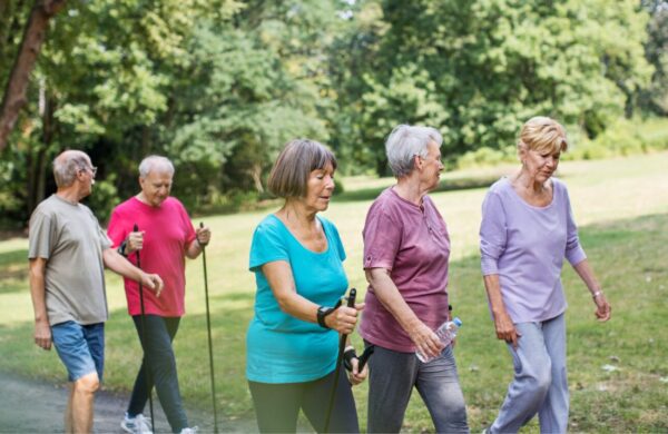 A group of five people walking through the park on a summer's day.