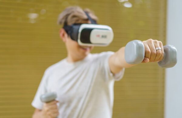A person wearing a VR headset and holding weights.