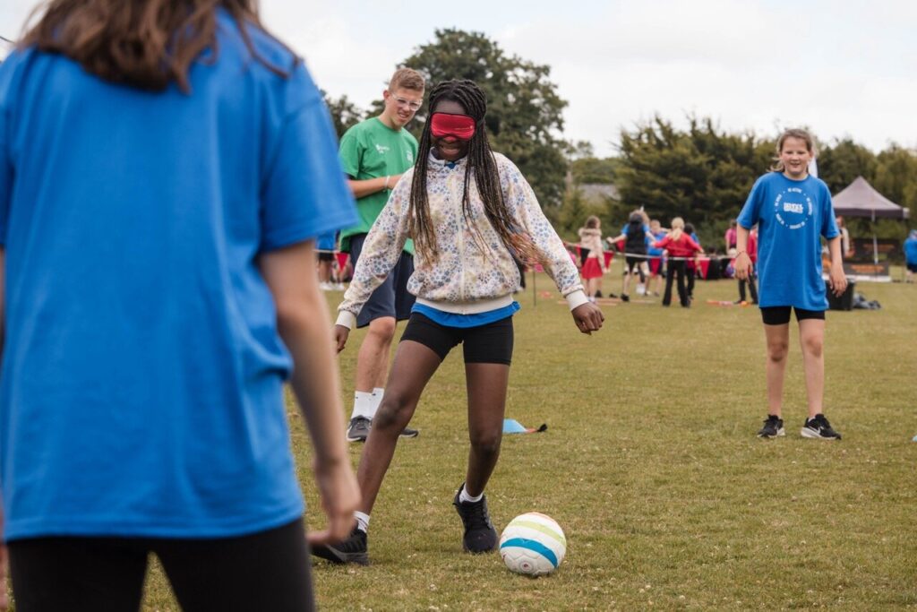 a young girl taking part in football wearing an blindfold
