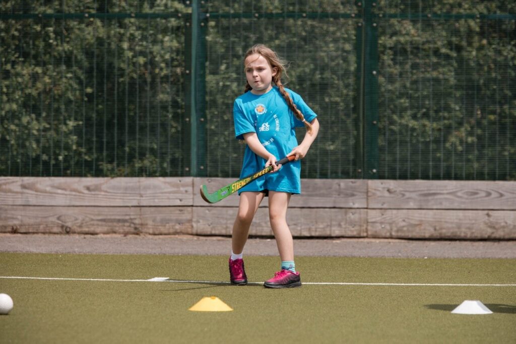 A young girl with a hockey stick.