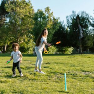 A mother and son throwing hoops onto sticks in the park.