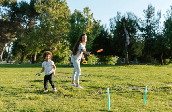 A mother and son throwing hoops onto sticks in the park.