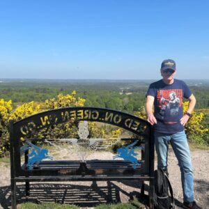 A man stood beside a bench overlooking a valley.