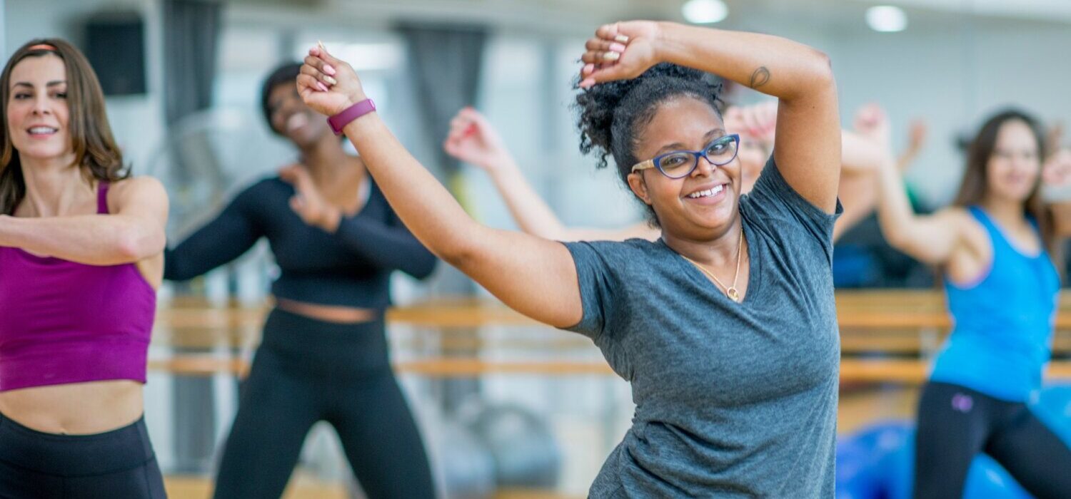 A woman dancing in a class with others.