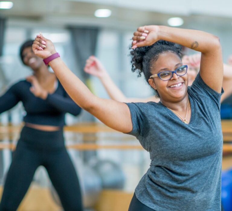 A woman dancing in a class with others.