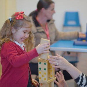 A little girl stacking blocks.