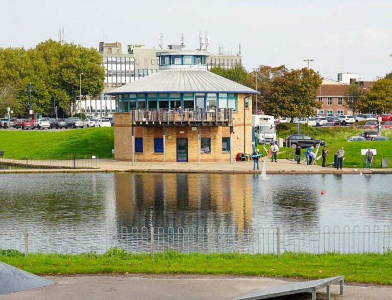 A round brick building beside a lake.