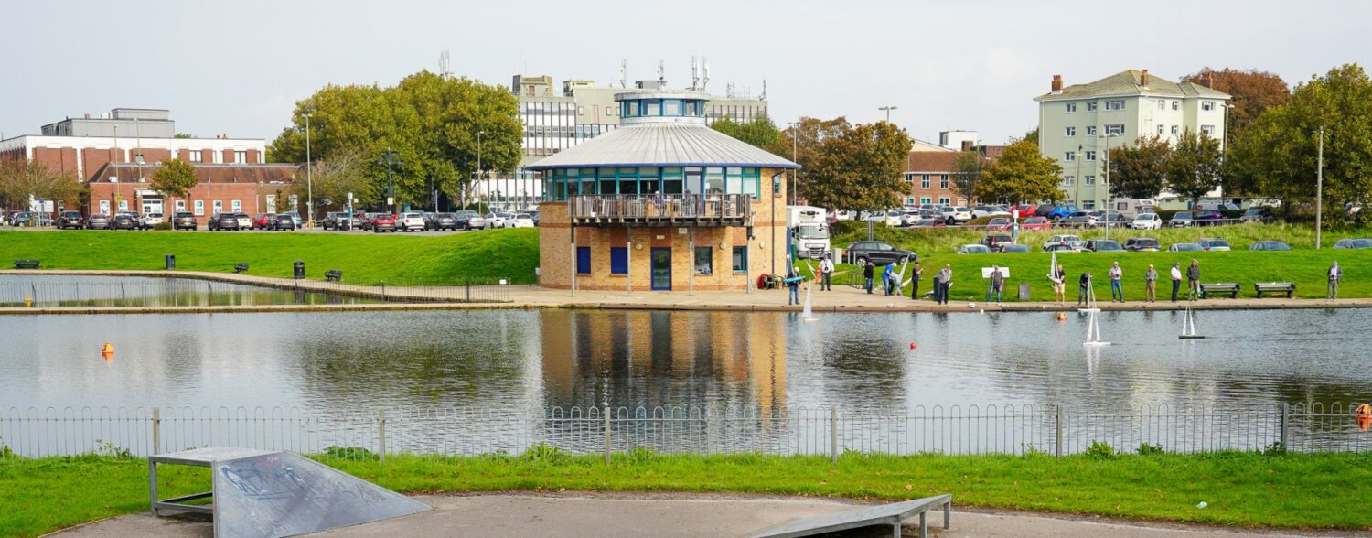A round brick building beside a lake.