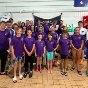 Locks Heath Swim Squad, a group of young people stood poolside. They're wearing purple squad t-shirts