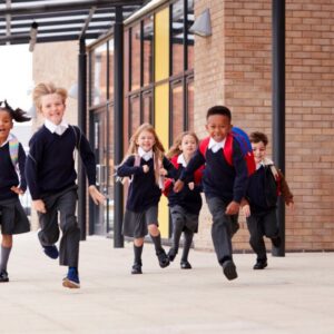 A group of children running in front of their school building.